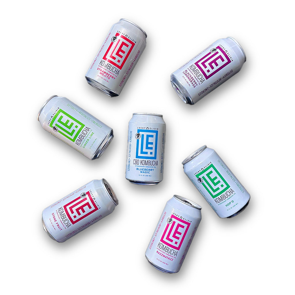 Assorted cans of Lucky Elixir Kombucha on a white background