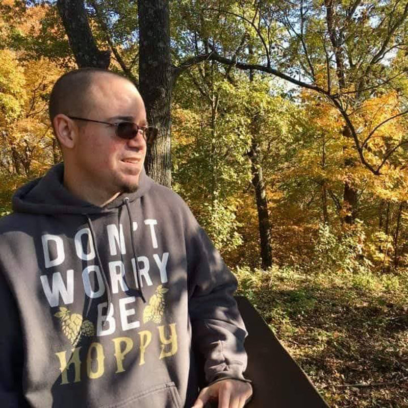 Person wearing a hoodie with 'Don't Worry, Be Happy' text in an autumn forest setting