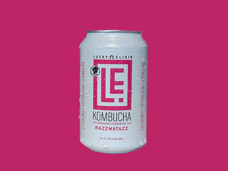 A can of Razzmatazz Kombucha by Lucky Elixir with a pink and purple label on a pink background.